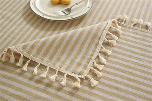 Close-up of beige and grey striped tablecloth with elegant fringe tassels and fabric texture