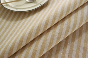 Detailed close-up of yellow and white striped linen tablecloth texture with rustic fringe