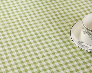 Detail der grün-weiß karierten Tischdecke mit einer weißen Keramik-Teetasse auf dem Stoff