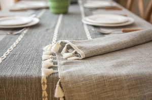 Close-up of grey jacquard table runner with white tassels and woven texture details