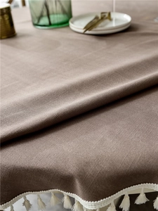 Detail of coffee brown linen texture with elegant white fringe trim on a round tablecloth