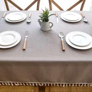 Close-up of grey waterproof tablecloth with elegant white fringe tassel detail on wood table