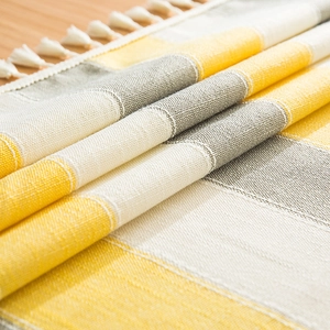 Close-up of ginger yellow and grey striped linen texture with elegant white cotton tassels