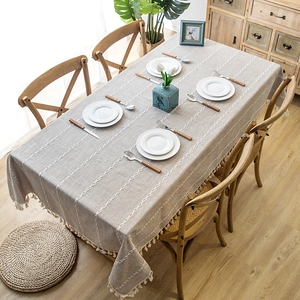 Linen texture tablecloth with geometric embroidery and fringe on a wooden dining table