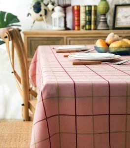 Macro shot of pink checkered tablecloth fabric with white tassels and dining setting
