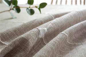 Close-up of beige linen tablecloth featuring white star embroidery and tassel details