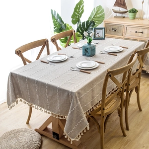 Close-up of grey linen tablecloth featuring white geometric embroidery and tassel edges