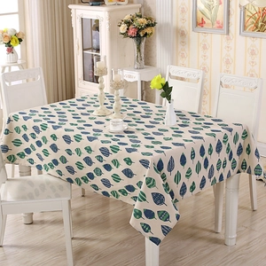 Detailed close-up of rectangle tablecloth with blue-green leaf pattern on beige fabric