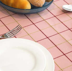 Detailed texture of pink plaid tablecloth with woven geometric patterns and fringe edges