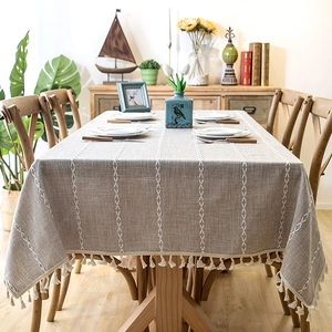 Detail of gray waterproof tablecloth featuring white embroidery pattern and decorative tassels