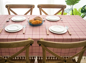 Detail of pink plaid tablecloth featuring white tassel fringe on linen-like fabric
