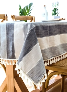 Close-up of navy and grey striped linen texture tablecloth with white cotton tassels