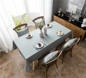 Detail of blue-grey cotton blend tablecloth with geometric woven lace edges and matching cushions