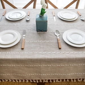 Detail of embroidered linen-textured tablecloth with decorative tassels and geometric patterns