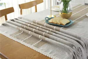Detail of gray beige plaid tablecloth with white lace edges on a wooden dining table