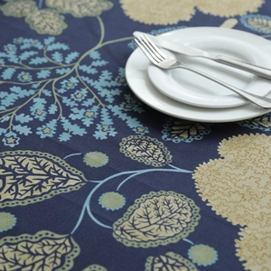 Close-up of thick cotton canvas tablecloth with blue leaf pattern and metal cutlery