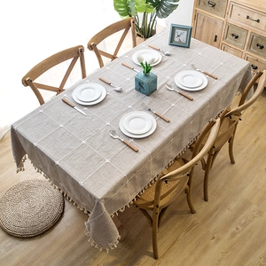 Nordic style grey linen tablecloth with white grid stitching and tassels on wooden table