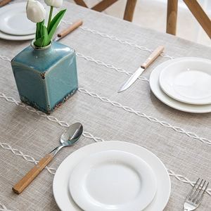 Close-up of geometric embroidery and tassels on a linen-style rectangular tablecloth