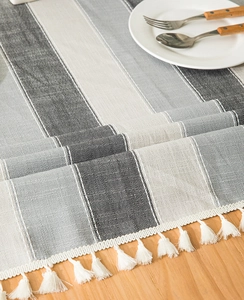 Close-up of striped faux linen table runner featuring elegant white fringe tassels