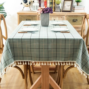 Green checkered tablecloth with cream tassels on a rectangular table in a cozy dining room