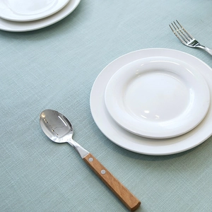 Close-up of minimalist stainless steel spoon with wooden handle and rivets on blue tablecloth