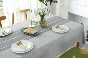 Close-up of grey jacquard tablecloth featuring detailed white lace trim and fringe