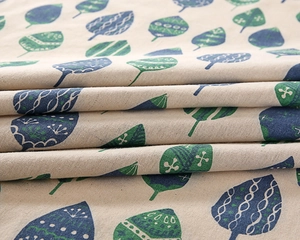 Close-up of cotton tablecloth fabric with blue and green leaf patterns and rich textures