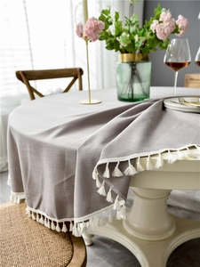 Detail of dark grey textured tablecloth featuring elegant white cotton fringe trim