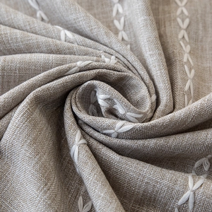 Detailed macro view of linen texture with white X-shaped embroidery and woven pattern