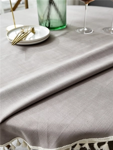 Detail of grey-purple linen-textured tablecloth with elegant white tassel fringe