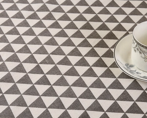Detail von grauem geometrischem Dreiecksmuster auf Tischdecke aus Leinen mit Tasse