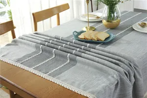 Detail of grey jacquard tablecloth with white lace edges and embroidered patterns