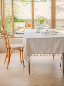 Close-up of beige faux linen tablecloth featuring woven stripes and tassel lace edges
