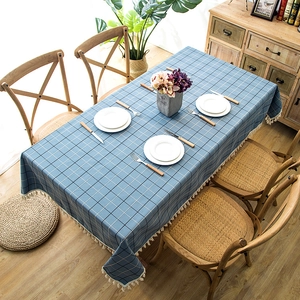 Close-up of blue geometric plaid tablecloth with tassel fringe on a wooden dining table