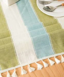 Macro detail of Nordic striped linen tablecloth showing fine weave texture and white tassels
