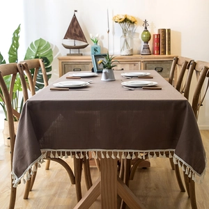 Detail of coffee brown faux linen tablecloth featuring white tassel fringe trim and texture
