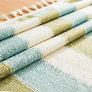 Macro detail of striped waterproof linen-blend tablecloth with decorative white fringe