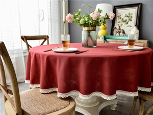 Close-up of red round cotton linen tablecloth with white tassel lace trim texture