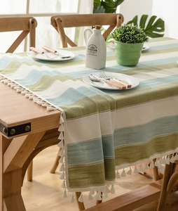 Detail of striped linen tablecloth with decorative white fringe on a wooden table