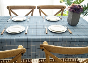 Close-up of blue geometric plaid tablecloth featuring decorative white tassel fringe edges