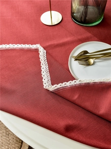 Close-up of red linen tablecloth featuring intricate white woven lace trim details