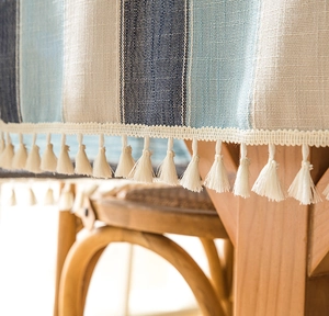 Close-up of blue and beige striped linen tablecloth with decorative tassel fringe edges