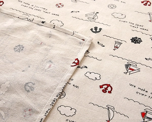 Detailed close-up of nautical cotton linen fabric with anchor prints and stitched edges