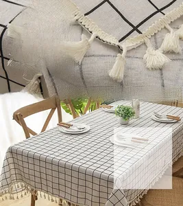 Detail of minimalist black and white checkered tablecloth featuring cream tassel fringe trim