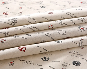 Macro detail of nautical print fabric showing sail ships, anchors, and cotton texture