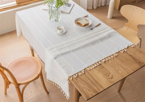 Close-up of beige cotton linen tablecloth with vertical jacquard and handmade tassel fringe
