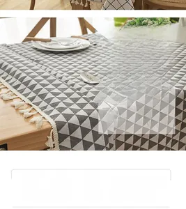 Detail of grey and white geometric cotton linen tablecloth with handmade tassels on wooden table