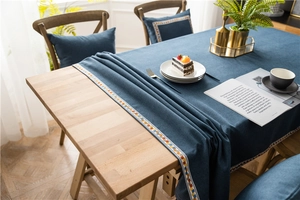 Close-up of navy blue rectangular tablecloth with geometric ribbon trim on a wooden table