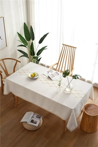Detail of waterproof beige tablecloth featuring yellow diamond embroidery and lace trim