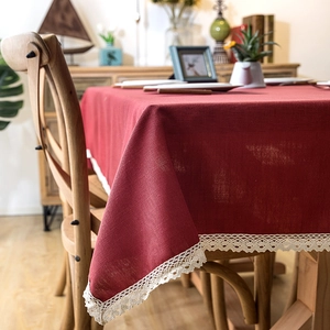 Detailed close-up of dark red linen tablecloth featuring elegant white lace fringe edges